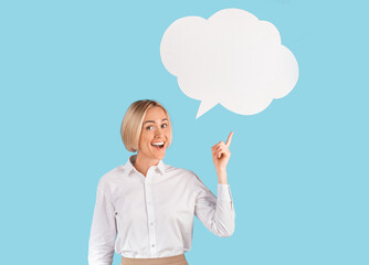 Happy mature business lady pointing at speech bubble on blue studio background, copy text