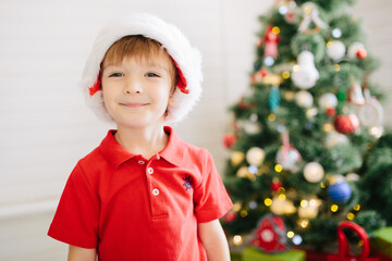 Cute little boy of about five year with a gift in a decorated Christmas room with a xmas tree