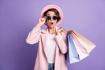 Photo of amazed pretty optimistic bob hair young lady hold bags wear glasses pink cap coat isolated...