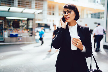 Serious businesswoman talking on smartphone on street