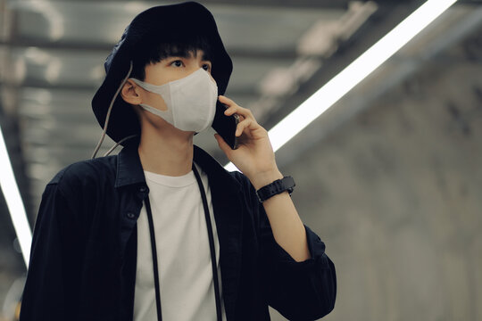 Asian man using smartphone with medical face mask to protect the Covid-19, new normal lifestyle