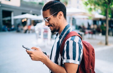 Smiling man in glasses surfing mobile phone