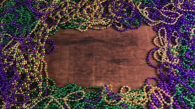flat lay border of colorful Mardi Gras beads with more beads hanging on side moving slightly