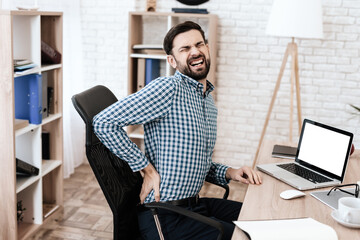 A man feels sharp pain in back and is twisting.