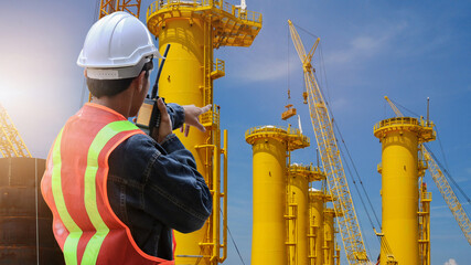 Engineer hand holding radio communication or Walkie Talkie on construction site background and...