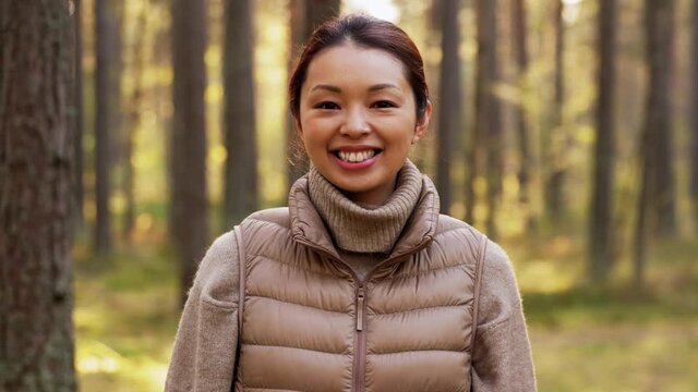 picking season, leisure and people concept - portrait of happy smiling asian young woman in forest