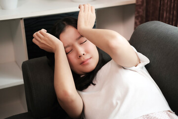 Young Asian woman is stressed and has a headache sleeping on the sofa