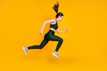 Fototapeta na wymiar Full length profile photo of sportive lady jump high up running wear sports suit shoes isolated yellow color background