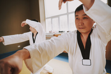 Karate players in kimonos stand and show tricks.
