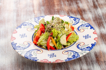 Homemade salad with fresh vegetables and microgreen on a decorative plate
