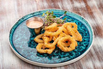 Squid rings fried in batter with sauce on a decorative plate