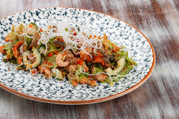 Salad with fried salmon belly, flying fish roe and  lettuce. On a decorative plate