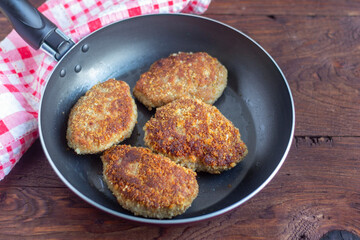 Juicy delicious chicken or Turkey cutlets in a frying pan on a dark wooden table. Rustic style. Selective focus, top view