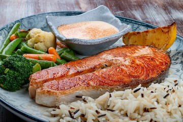 Salmon steak with cheese sauce, blanched vegetables and wild rice