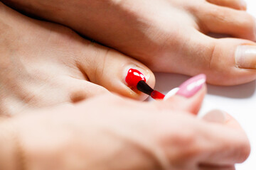 Manicure and pedicure at white background.Woman at home spa doing pedicure to herself in white background, close-up. © Serhiy Chaiko