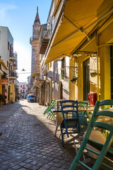 Fototapeta na wymiar Early morning in old narrow streets of Chania, Crete, Greece and historical monument of Ottoman era - Ahmet aga minaret. Street cafes and restaurant