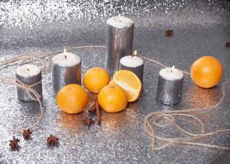 burning candle on silver background with oranges