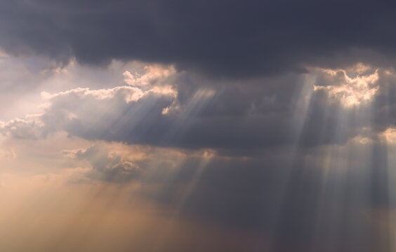 The sun's rays passing through the clouds and shining form an interesting light pattern against the sky. Copy space. Selective focus. © num
