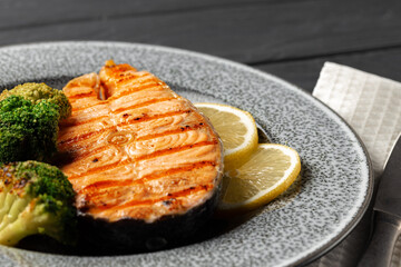 Grilled salmon steak with broccoli on grey plate