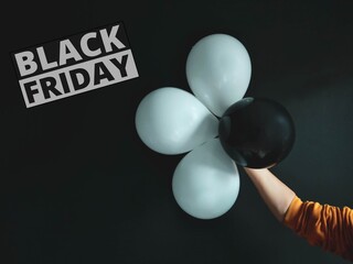 
female hand holding black and white balls on black background photo for black friday theme 