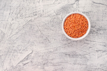 Red lentils in white plate on white stone background. Vegetarian super food.