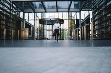 Mature corporate boss with stylish briefcase and modern smartphone gadget in hand going out from own company office and thinking, Caucasian middle aged businessman at urban setting with enterprise