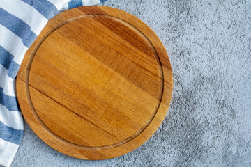 Round wooden cutting Board on a blue-gray background with a copy of the space.