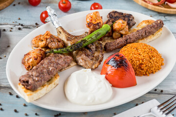 Mixed grill on wooden table. Lamb chops, Adana kebab, chicken shish, shish meatballs, steak.