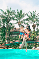 Naklejka premium Asian mother and little son enjoying swimming in a swimming pool in summer vacation.