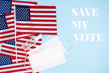 Flat lay composition with american flags, disposable protective masks and sanitizer on blue background with inscription SAVE MY VOTE. National symbol. Safe Election Day and healthcare concept