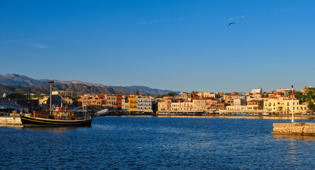 Obraz premium Beautiful view of Old Venetian harbour of Chania, Crete, Greece, quayside, tourist boats by piers in early morning. Cretan mountains in background.