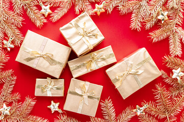 Red Christmas or new year's background,plain composition of golden Christmas gifts and golden fir branches with christmas toys,Flatlay,empty space for greeting text.christmas concept.