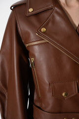 Brown leather jacket with metal zippers on it. Girl in a stylish white jacket. Stitched leather. Closeup. Vertical fashion background.