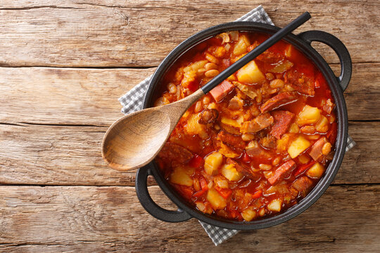 Locro stew of squash, beans, corn, potatoes, sausages and meat close-up in a pot on the table. horizontal top view from above
