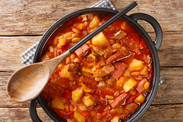 South American Locro stew of pumpkin, beans, corn and meat close-up in a pot on a table. horizontal top view from above