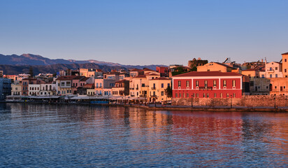 Fototapeta na wymiar Sunrise view of Old Venetian harbour, Chania, Crete, Greece, its quay.Maritime museum of Crete in first sunrays. Cretan hills and mountains 