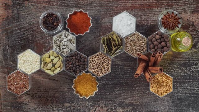 Spices in hexagonal jars on a wooden surface. Stop motion animation