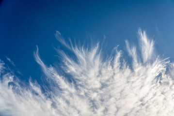 frayed cirrus clouds on deep blue sky