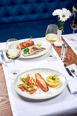 Fish dishes and white wine on a table in a restaurant.