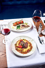 Two fish and meat dishes on a table in a restaurant.