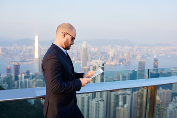 Serious businessman using tablet while having break on rooftop of modern office
