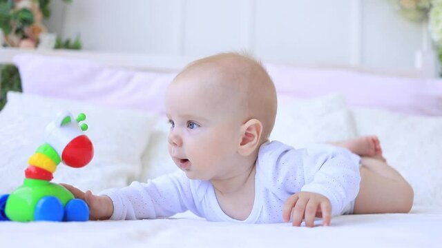 a child plays with a rattle on the bed at home
