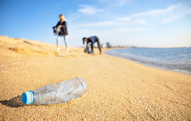Teamwork cleaning plastic on the beach. Volunteers collect trash and plastic bottle in a bag....