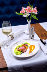 A glass of wine and a tuna dish in a restaurant.
