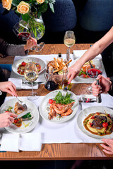 Hands of four people at a table with food.