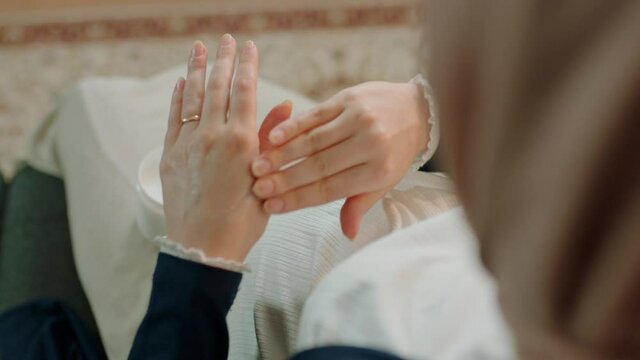 Pregnant Muslim woman is applying hand cream.Close-up hands. Shooting from the shoulder. Skincare concept.
