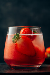 Delicious strawberry cocktail with ice on dark background