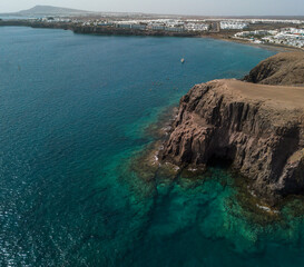 Aerial view of the jagged shores and beaches of Lanzarote, Spain, Canary. Roads and dirt paths. Walking routes to explore the island. Bathers on the beach. Atlantic Ocean. Papagayo
