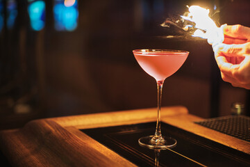 Pink Cosmopolitan vodka cocktail with flame