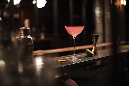 Pink Cosmopolitan vodka cocktail on the vintage bar with shaker